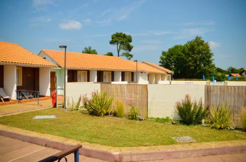 una casa con techo naranja y valla en Hotel Les Pins, en Hourtin