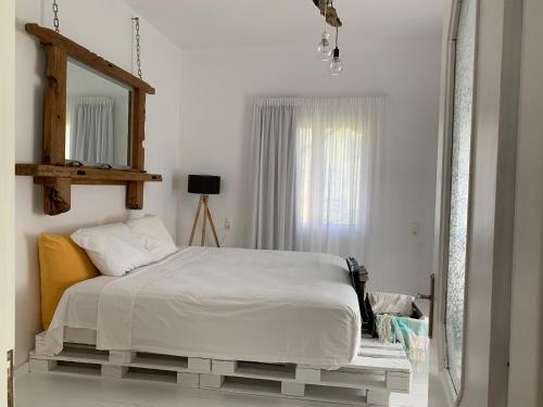 a white bedroom with a bed and a mirror at Farmers House in Magarikárion
