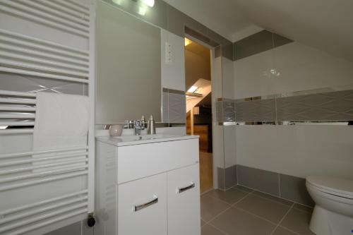 biała łazienka z umywalką i toaletą w obiekcie Mária Apartman Pécs w mieście Pecz