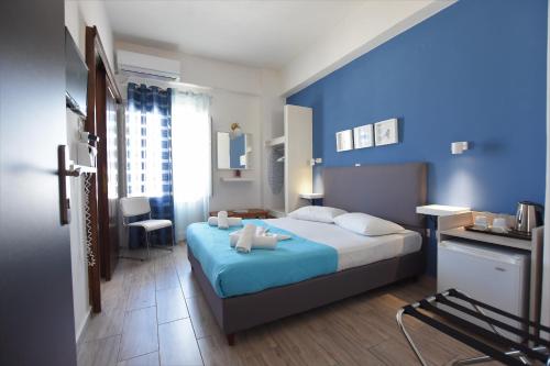 a bedroom with a bed and a blue wall at Rodakas Hotel in Akrotiri