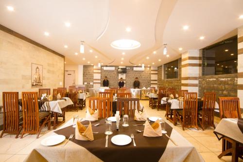 een restaurant met tafels en stoelen en mensen op de achtergrond bij Hotel Dharamshala Paradise in Dharamshala