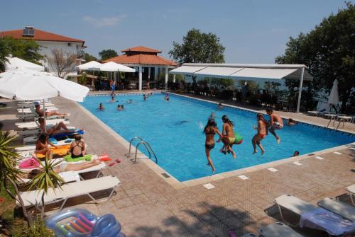 a group of people jumping into a swimming pool at Hotel Camping Agiannis in Makrýgialos