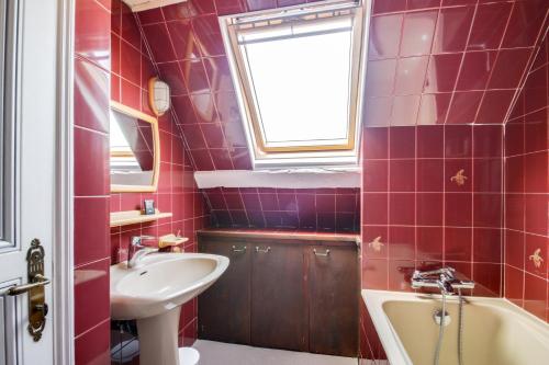 baño con azulejos rojos, lavabo y ventana en Le Corsaire de Solidor, en Saint-Malo