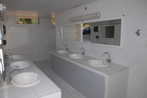 a bathroom with three sinks and two mirrors at Hotel Camping Agiannis in Makrýgialos