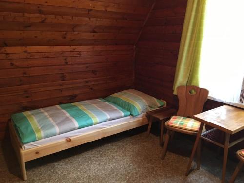 a bed in a log cabin with a table and a chair at Chata Pod Bílým kamenem in Doksy
