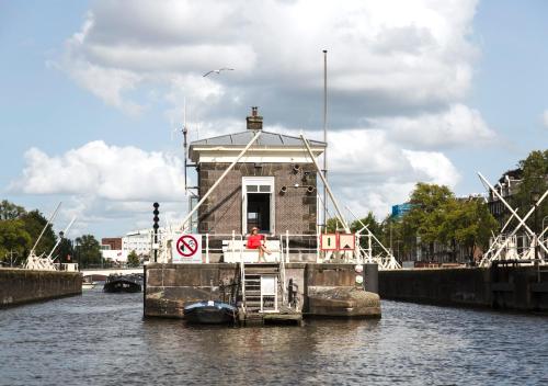 a person standing on a boat in the water at SWEETS - Amstelschutsluis in Amsterdam