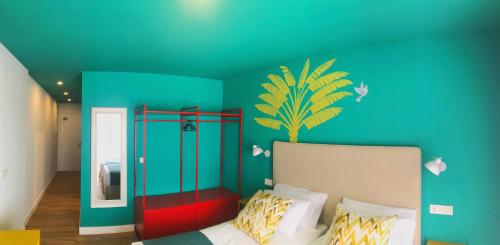 a bedroom with a blue wall with a bed and a mirror at Hotel Ritual Maspalomas - Adults Only in Playa del Ingles