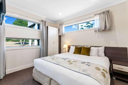 a bedroom with a bed and two windows at Comfort Inn & Suites Warragul in Warragul