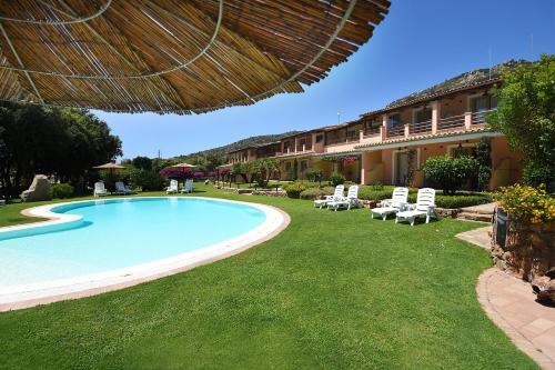 a swimming pool in a yard next to a building at Hotel Su Giganti in Villasimius