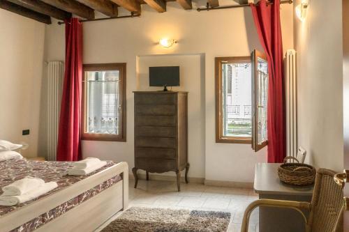 a bedroom with red curtains and a bed and a desk at La Gondola - beautiful canal view in Venice