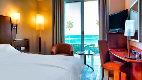a hotel room with a bed and a desk and a window at Bull Reina Isabel & SPA in Las Palmas de Gran Canaria