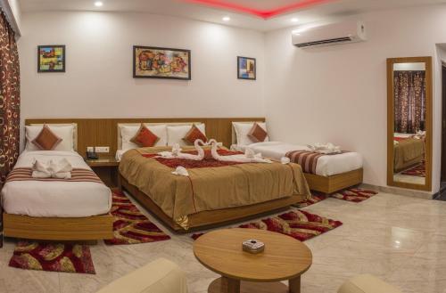 a hotel room with two beds and a table at Hotel Suktara International in Siliguri