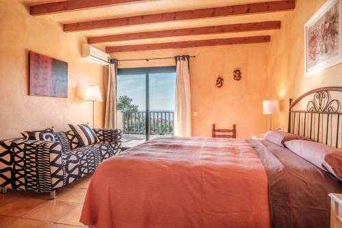 a bedroom with a bed and a chair and a window at Villa Ses Marjades in Cala Vadella