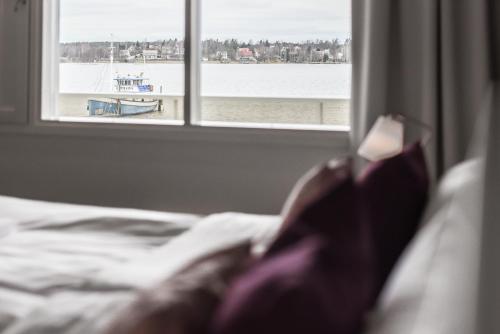 a bed with a window looking out at the water at Hotel Sea Front in Tammisaari