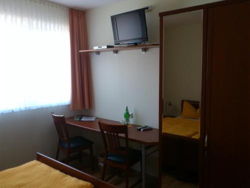 a room with a table with chairs and a television at Eifel - Pension in Kall
