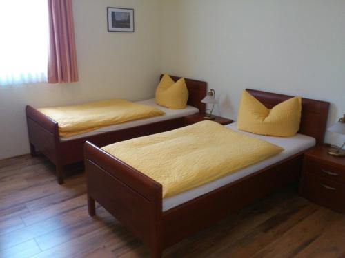 two beds with yellow pillows in a room at Eifel - Pension in Kall