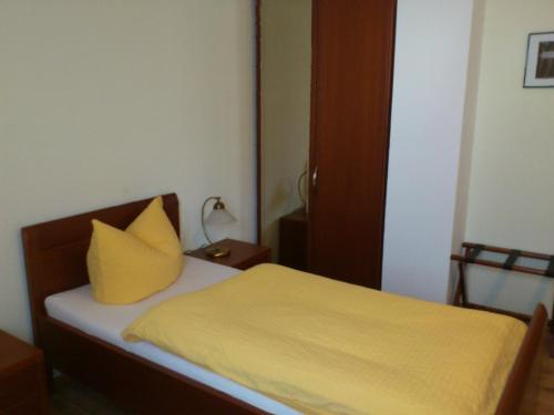 a bedroom with a yellow pillow on a bed at Eifel - Pension in Kall