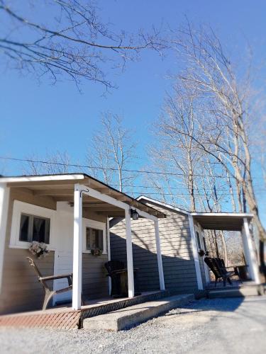 a white house with a porch and trees at Rothesay Motel in Rothesay