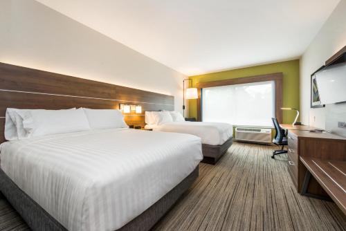 a hotel room with two beds and a flat screen tv at Holiday Inn Express & Suites - Carrollton West by IHG in Carrollton