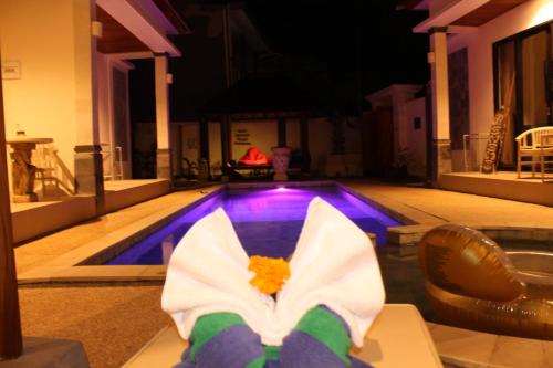 a person with their feet up in front of a swimming pool at Villa Viking in Jimbaran