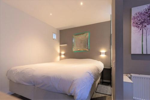 アムステルダムにあるBed & Bike Studio Amsterdamの白いベッドと壁に絵画が飾られたベッドルーム1室