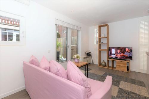 a pink couch in a living room with a tv at B&B Bike Studio Amsterdam in Amsterdam