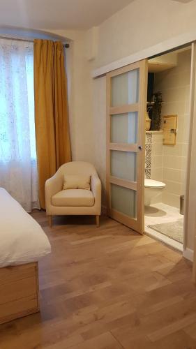 a bedroom with a bed and a chair and a bathroom at A la liberté in Salins-les-Bains