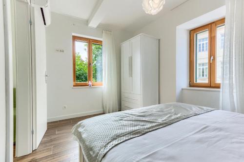 a white bedroom with a bed and two windows at St.Lucija in Split