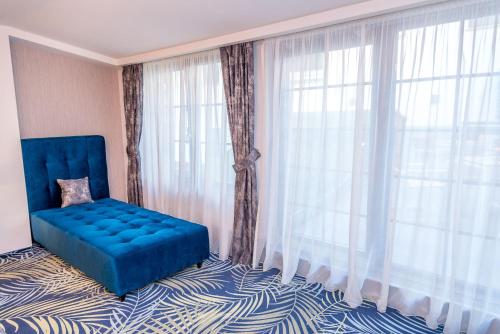 a room with a blue chair in front of a window at ART Hotel in Sibiu