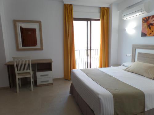 a bedroom with a bed and a desk and a window at Hotel Goya in Almuñécar