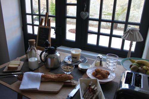 una mesa con comida y bebidas y ventanas en L’Ostréale, en La Tremblade