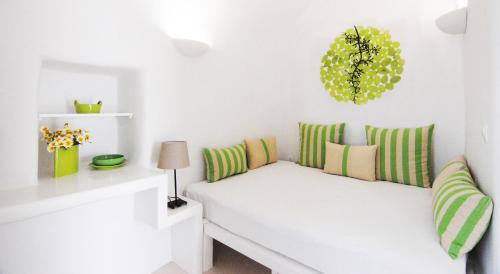 Pokój z białą kanapą z zielonymi i żółtymi poduszkami w obiekcie White Grape Suites w mieście Oia