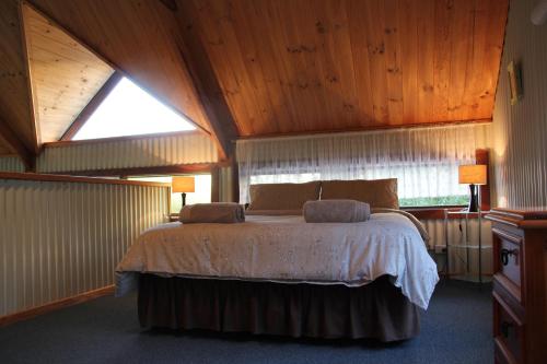 ein Schlafzimmer mit einem Bett in einem Zimmer mit Holzdecken in der Unterkunft Lakeside Garden Chalet in Denmark