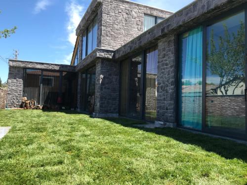 a stone house with large windows on a lawn at HemDem Alçıtepe in Canakkale