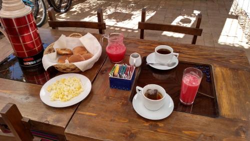 een houten tafel met ontbijtproducten en drankjes erop bij Ruta Alterna Hostel in Cajamarca