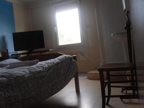 a living room with a couch and a tv and a window at l'escale gourmande in Châlus