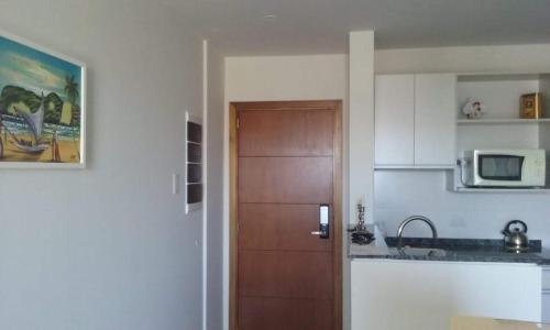 a kitchen with a wooden door and a microwave at Opera Villa Carlos Paz in Villa Carlos Paz