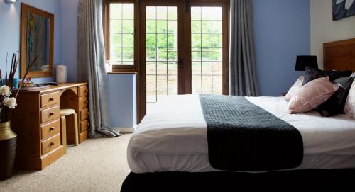 a bedroom with a bed and a dresser and a window at Little Foxes Hotel & Gatwick Airport Parking in Crawley