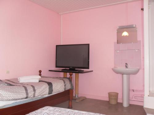 a bedroom with a bed and a tv and a sink at l'escale gourmande in Châlus
