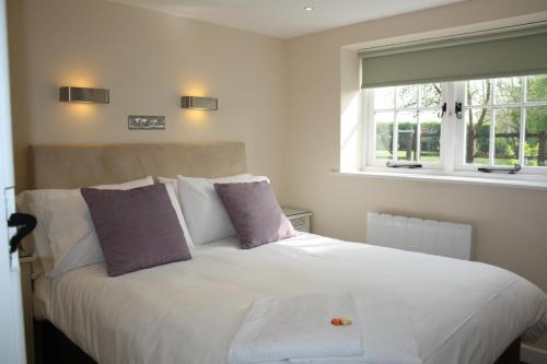 um quarto com uma cama branca com almofadas e uma janela em The Rectory Lacock Cottages em Lacock