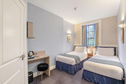 a hotel room with two beds and a desk at The Judd Hotel in London