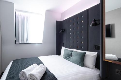 a bedroom with a large bed with towels on it at Point A London Liverpool Street in London