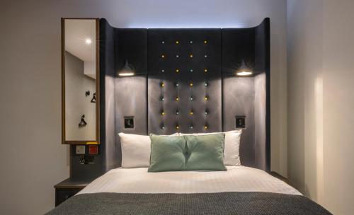 a bedroom with a large bed with a large headboard at Point A London Liverpool Street in London