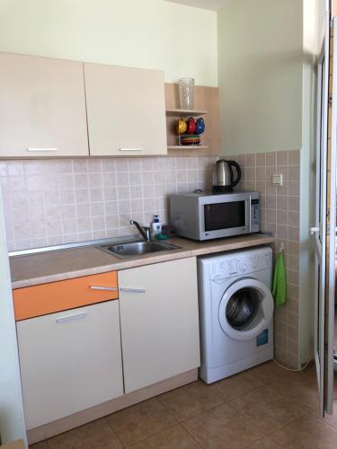 eine Küche mit Waschmaschine und Mikrowelle in der Unterkunft Elit 2 Apartment in Sonnenstrand