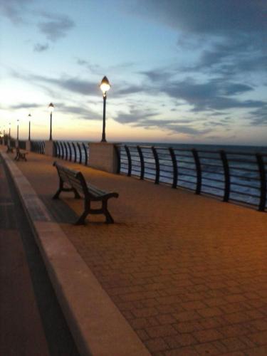 a row of benches on a sidewalk near the ocean at Villa Longo de Bellis in Bari