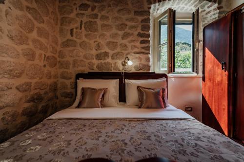 uma cama num quarto com uma parede de pedra em Magnolia apartment em Kotor