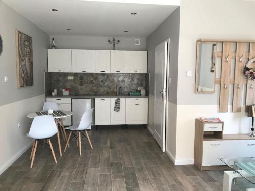 een keuken met witte kasten en een tafel en stoelen bij Rubinowe Apartamenty in Sandomierz