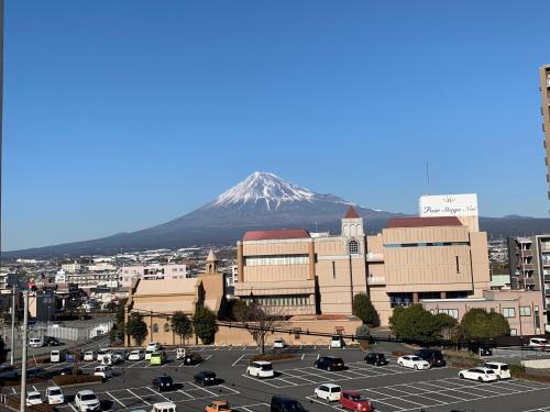 a mountain in the background of a city with a parking lot at Super Hotel Fuji Inter in Fuji