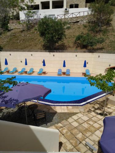a swimming pool with chairs and umbrellas next to a building at Sfinias Apartments in Kali Limenes