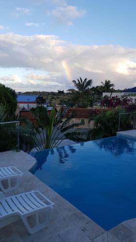 a blue pool with a rainbow in the background at C'Renity Studio in Cul de Sac